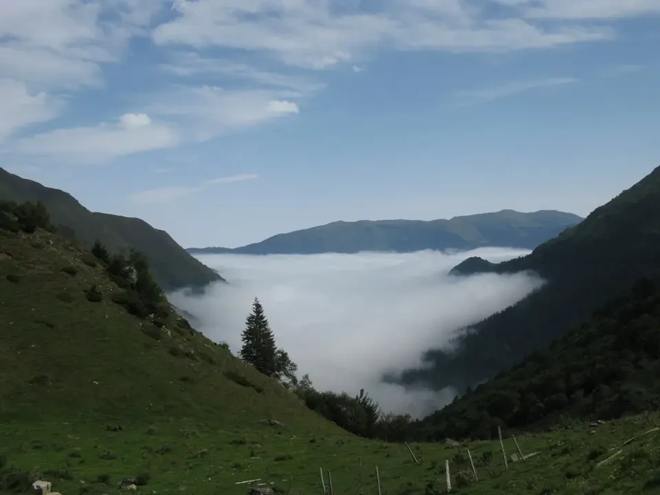 Panorama montano dei Pirenei avvolto dalla nebbia mattutina.