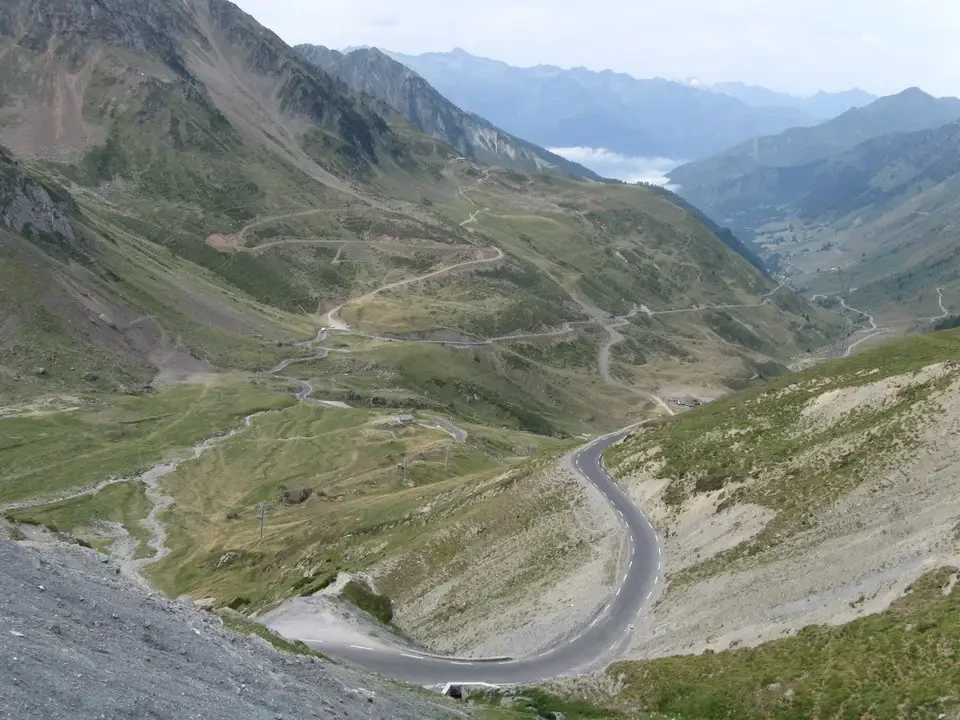 Una strada sinuosa attraversa un paesaggio montano nelle Alpi Pirenaiche.
