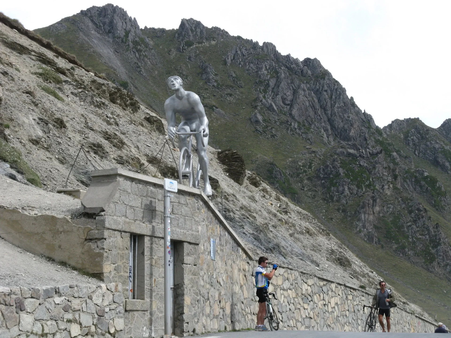 Una statua maschile è posizionata su un muretto lungo una strada montana nei Pirenei.