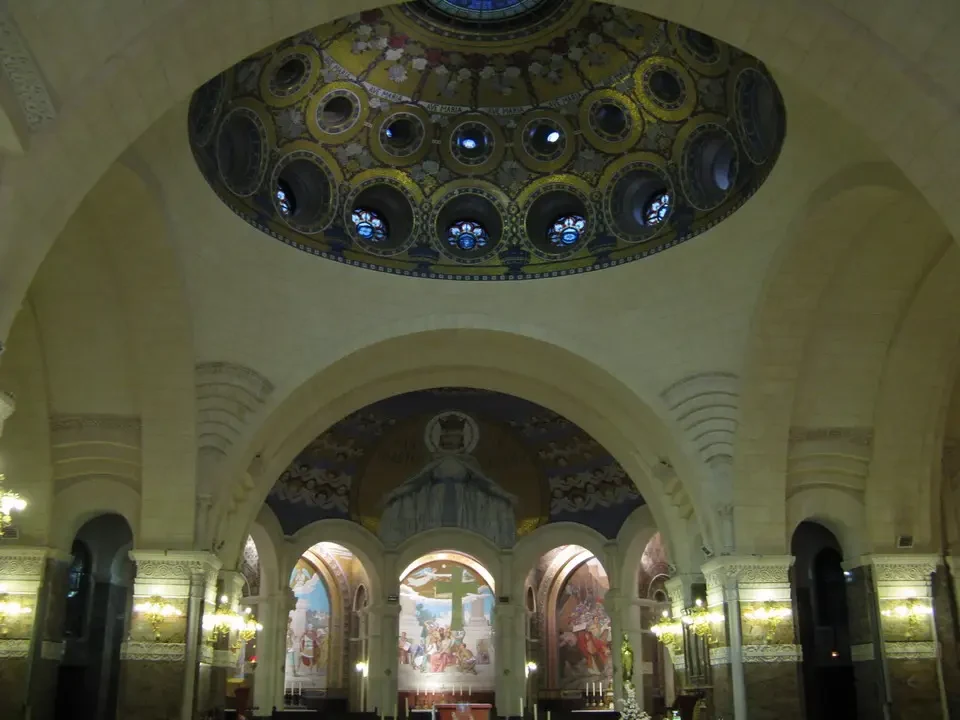 Interni sontuosi di una basilica con volte decorate e mosaici dorati.
