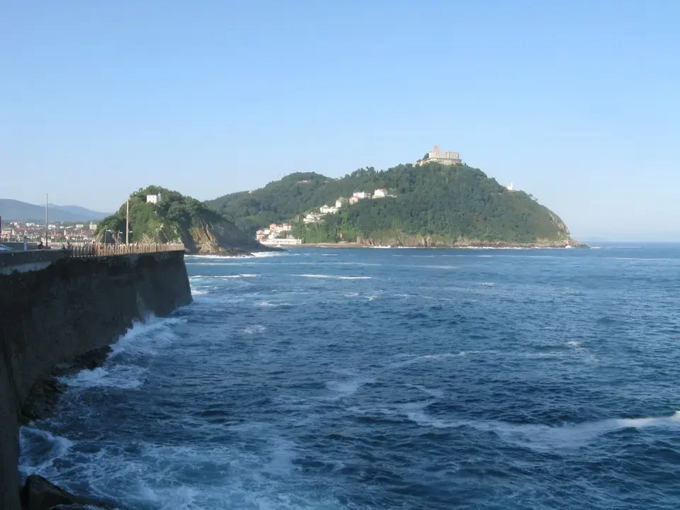 Vista costiera con fortificazione e isola verde nel Mediterraneo.