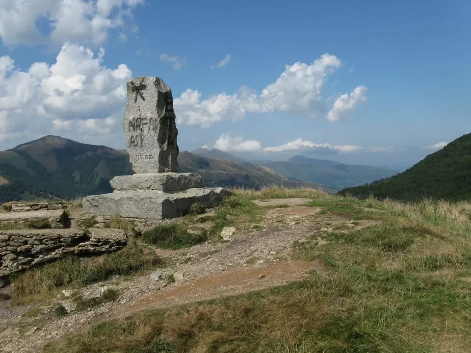 Una stele antica si erge su un crinale montano con vista panoramica.