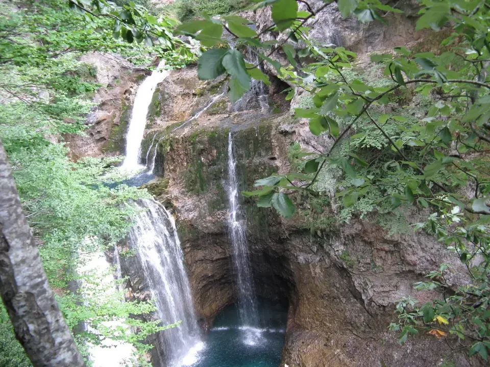 Cascate d'acqua smeraldo scendono attraverso una gola rocciosa nei Pirenei.