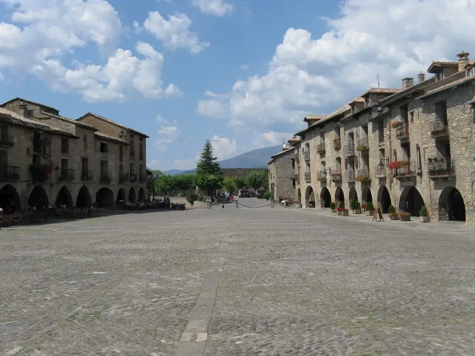 Una vista ampia di una piazza pavimentata con edifici storici in stile arcubarcato.