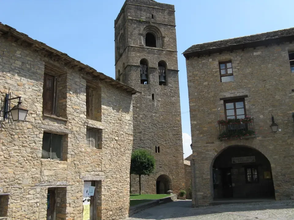 Vista di un borgo in pietra con una torre centrale nei Pirenei.