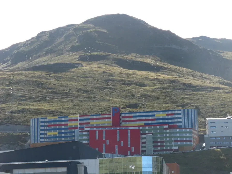 Paesaggio montano verde con un edificio colorato in primo piano.