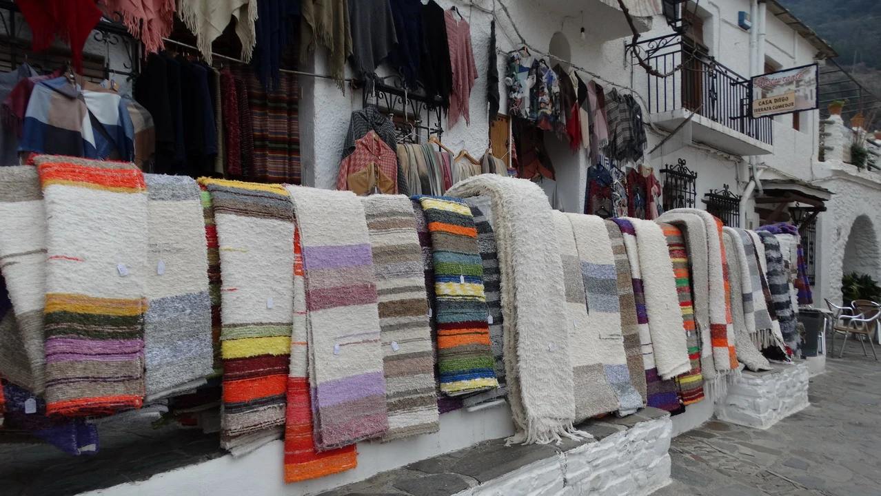 Una fila di coperte colorate è esposta all'aperto in una strada di Andalusia o Algarve.