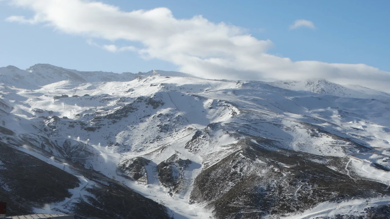 Paesaggio montano innevato con nuvole basse coprono le vette.