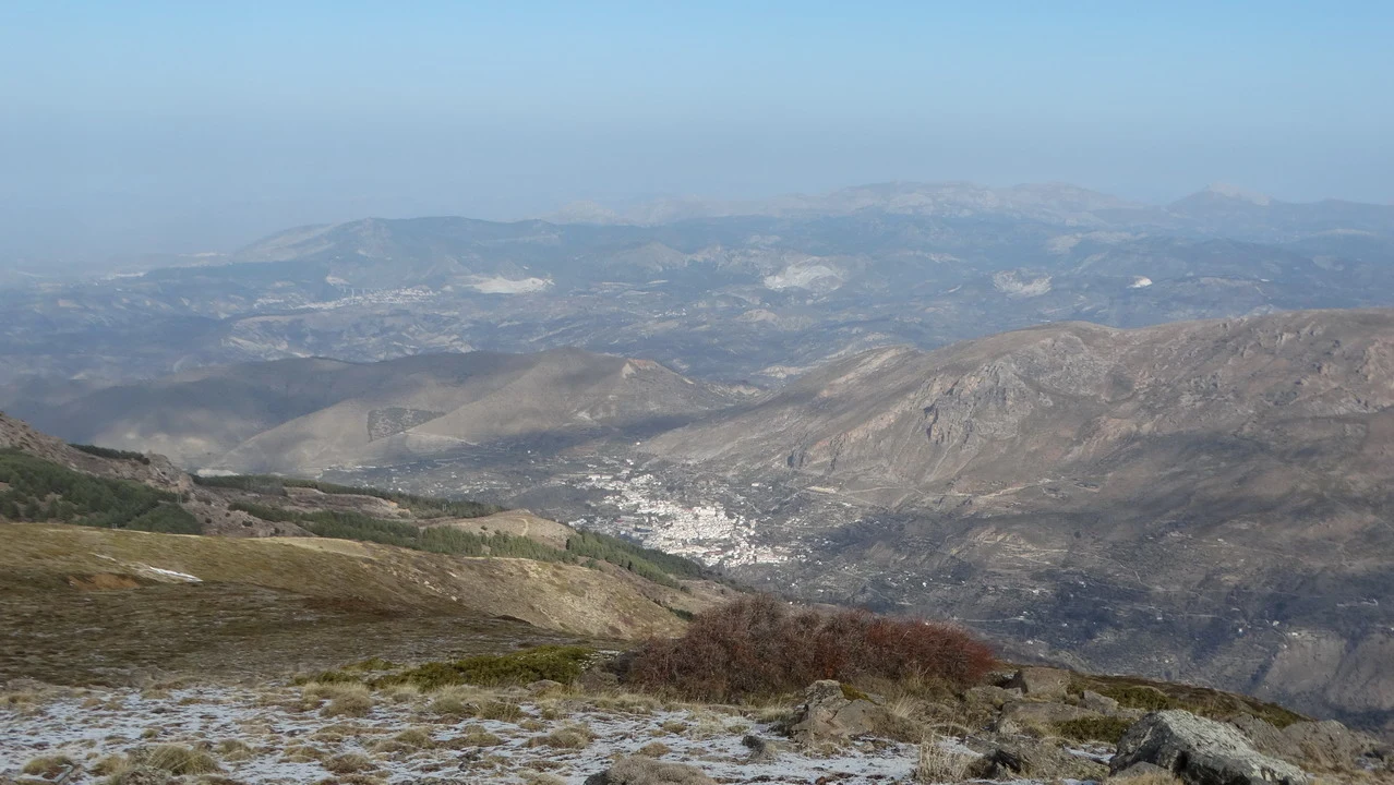 Paesaggio montano vasto con colline ondulate sotto un cielo limpido.