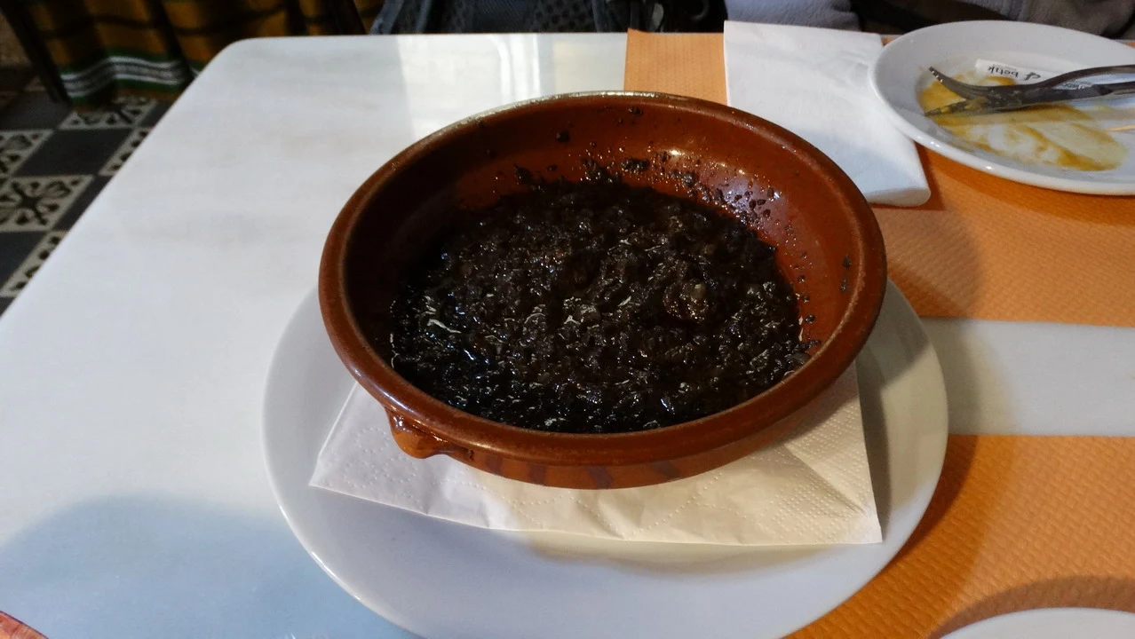 Un piatto scuro di cibo viene servito su un tavolo all'aperto.