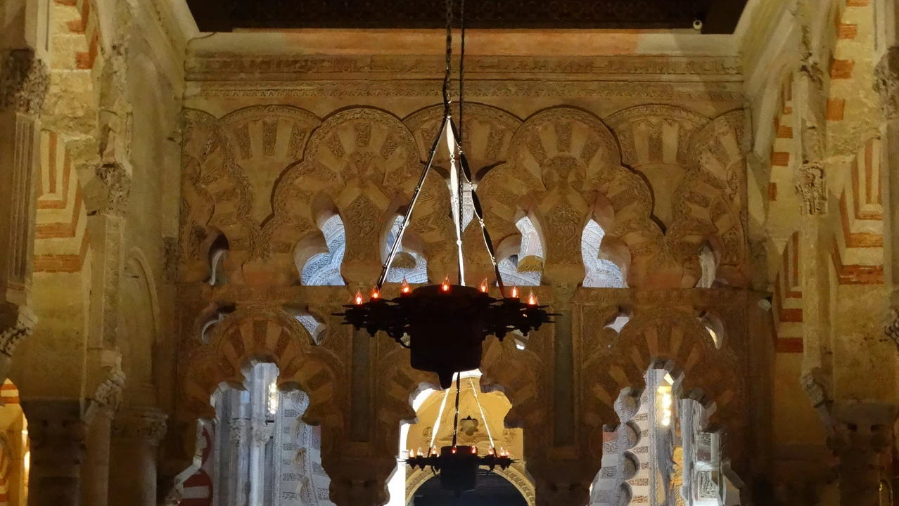 Interno maestoso della Mezquita di Cordova con archi decorati in pietra.