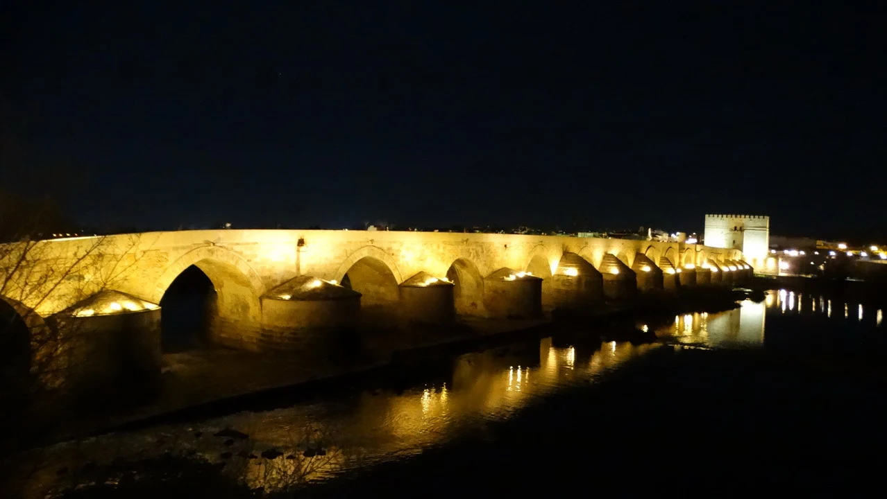 Ponte romano illuminato di notte lungo il fiume.
