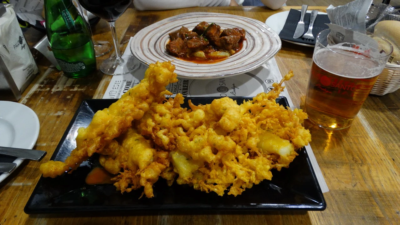 Cena in un ristorante in Andalusia o Algarve con piatti di cibo fritto e carne.
