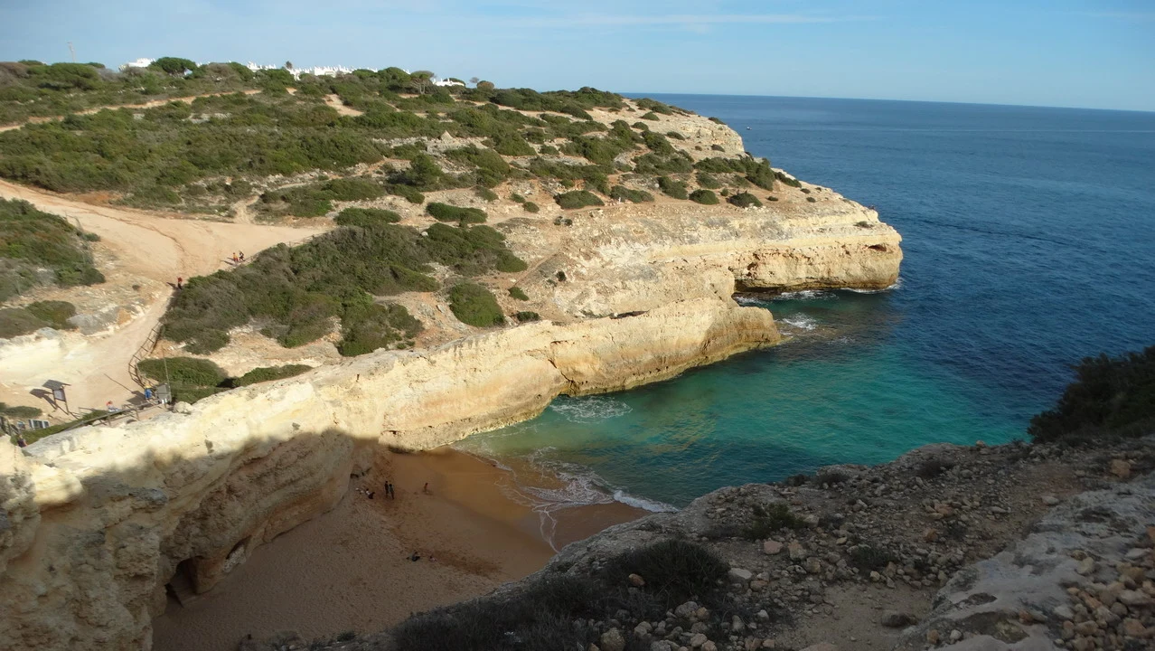 Paesaggio costiero roccioso con acqua turchese sotto il sole.