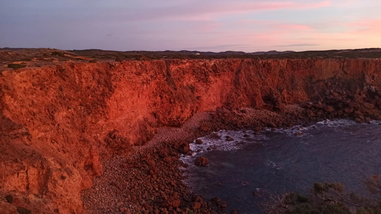 Paesaggio costiero rosso fuoco all'alba tra Andalusia e Algarve.