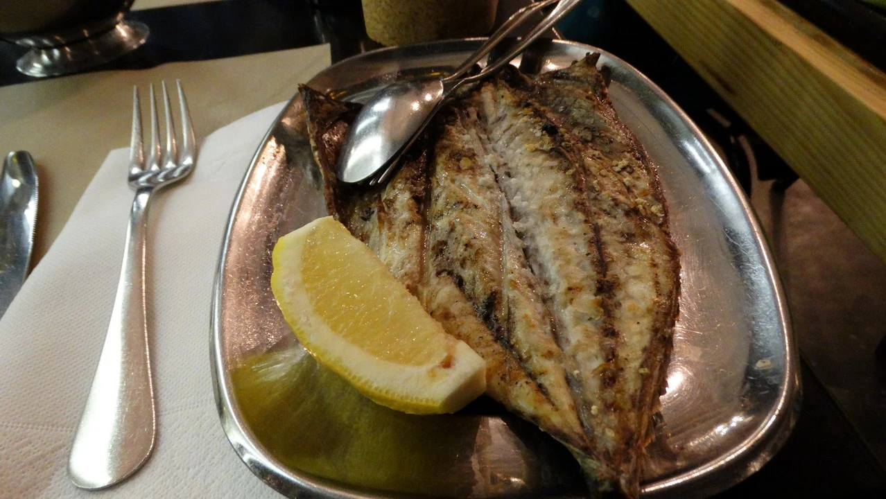 Pesce grigliato con limone su un piatto di metallo.