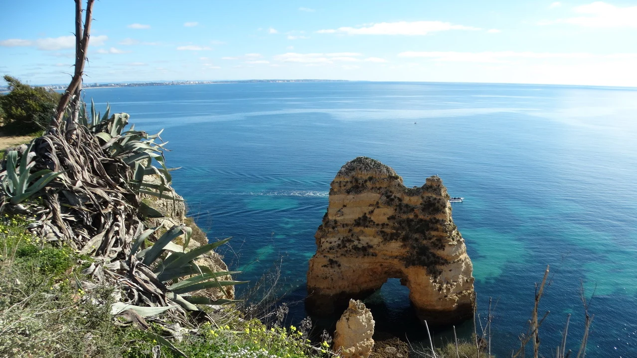 Paesaggio costiero con scogliere rocciose che si tuffano nell'acqua turchese.