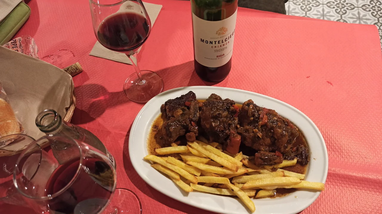 Un tavolo apparecchiato per una cena con cibo e vino in un contesto di viaggio.