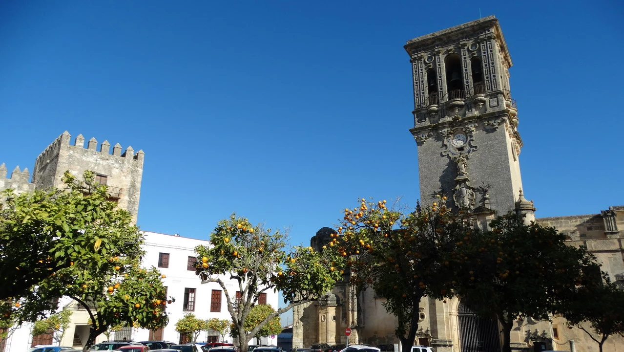 Vista di una torre storica in un contesto di città andalusa o algarvia con alberi frondosi.