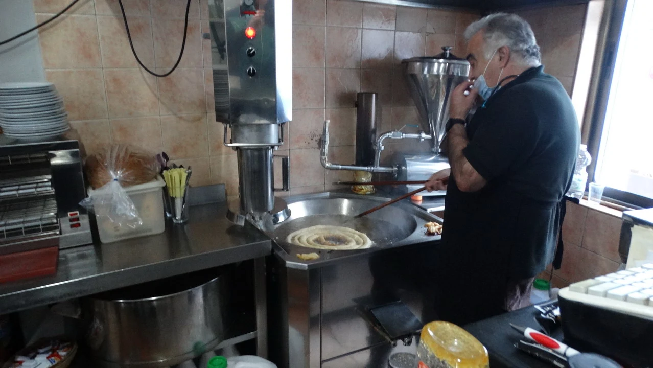 Un uomo prepara churros in una cucina professionale.