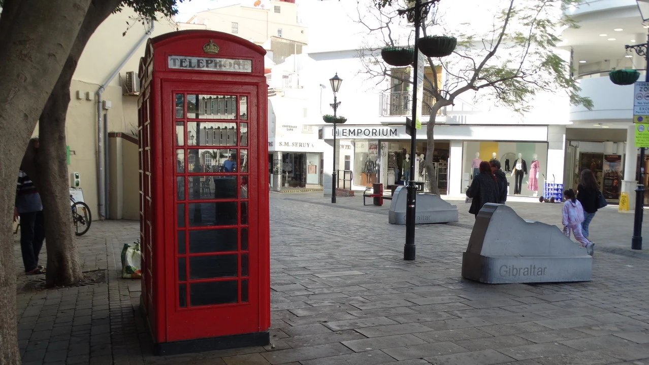 Una strada pedonale con un telefono rosso in primo piano in una località della Spagna.