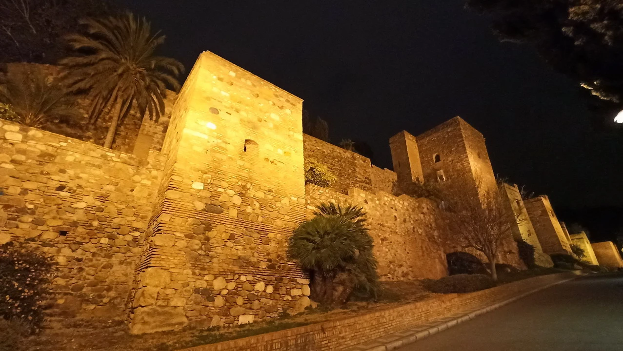 Mura in pietra illuminate al tramonto mostrano un castello storico in Andalusia.