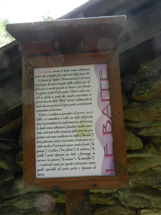 Una vista esterna di una struttura in legno con un muro di pietra alla base.