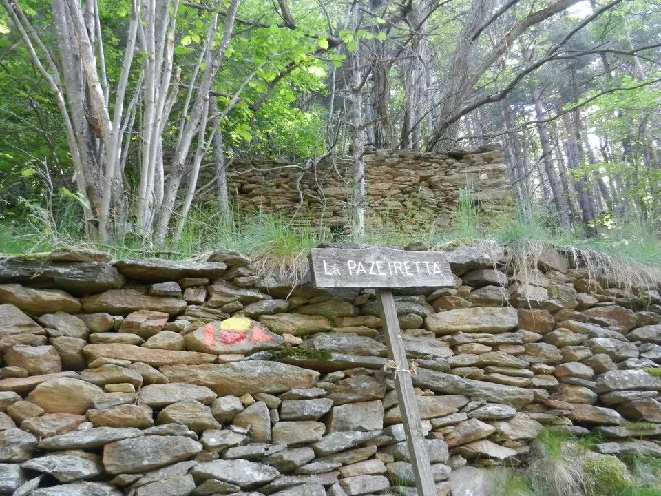 Muro in pietra con un cartello sulla Via dei Sentieri.