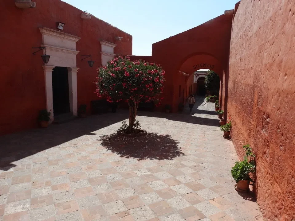 Cortile interno di un monastero in mattoni rossi con archi e piante.