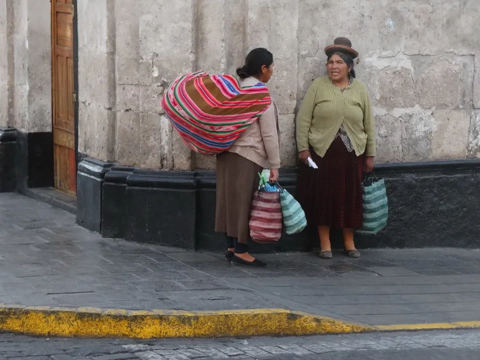 Due donne in abiti tradizionali passeggiano lungo una strada in Perù o Bolivia.