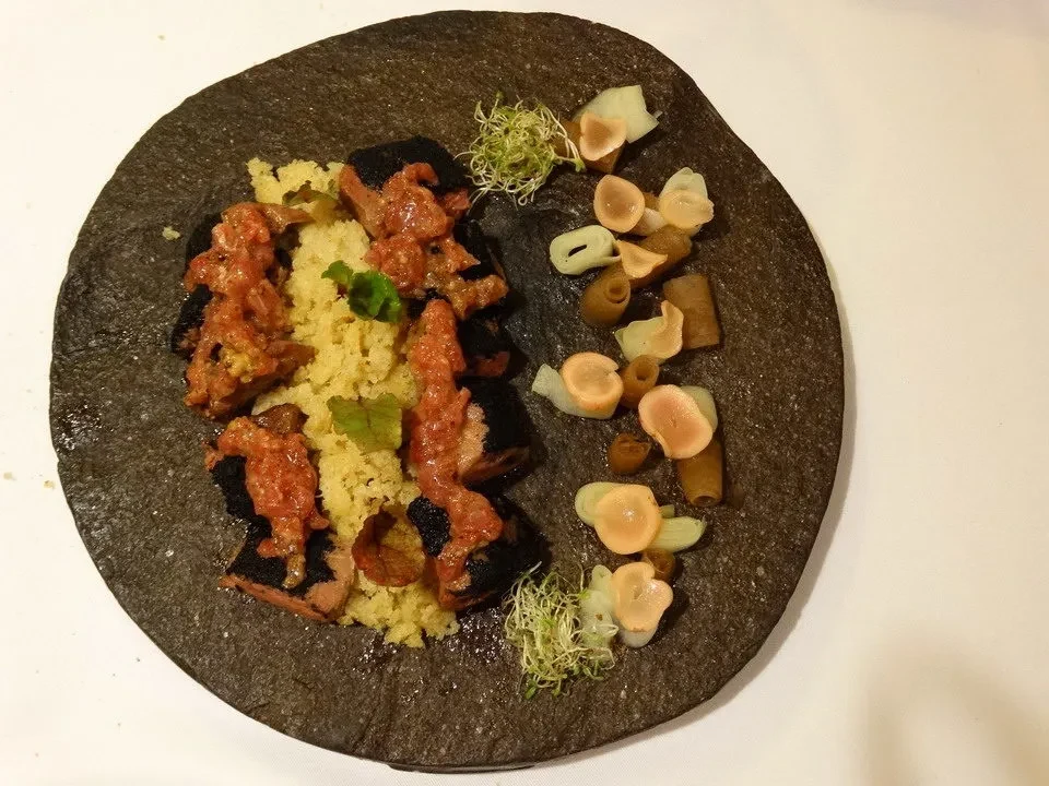 Un piatto di cibo servito su una teglia scura con accompagnamenti vegetali.