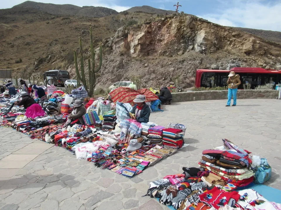 Mercato all'aperto con venditori di tessuti in un paesaggio montano del Perù e della Bolivia.