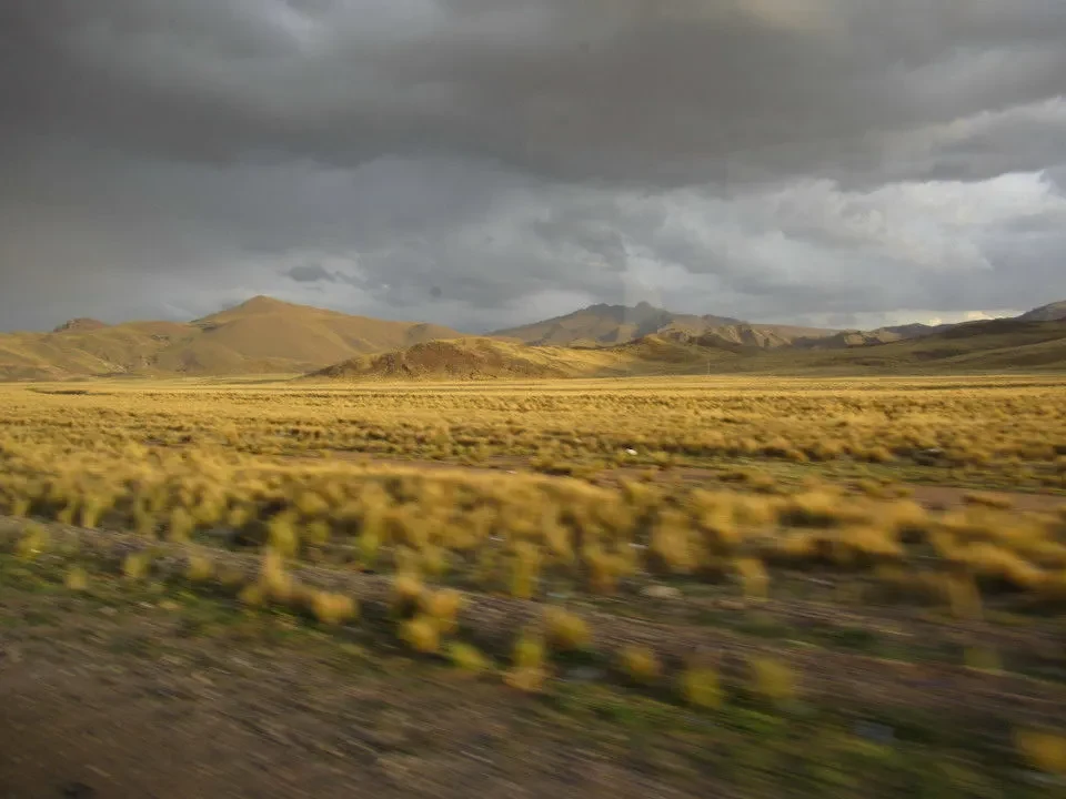 Paesaggio vasto di pianura e montagne in Perù e Bolivia sotto un cielo nuvoloso.