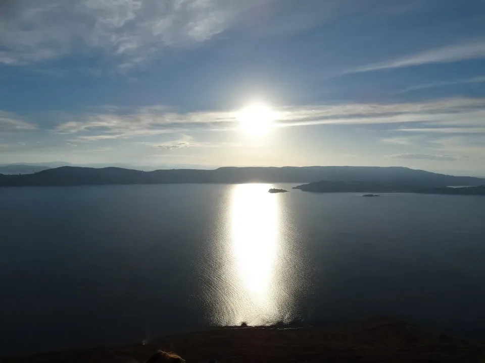 Riflesso del sole sull'acqua in un paesaggio andino.
