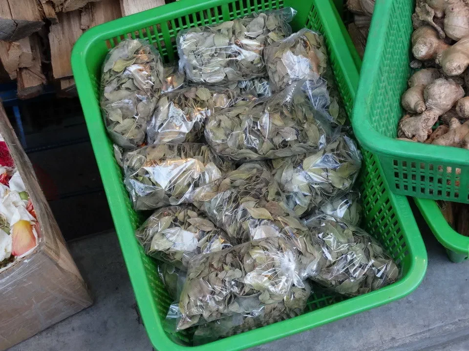 Un mucchio di erbe secche e patate sono esposti in una cassa verde sul mercato andino.