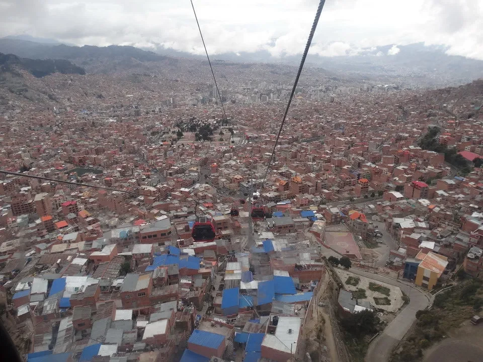 Vista aerea della città di La Paz in Perù con montagne circostanti sotto un cielo nuvoloso.
