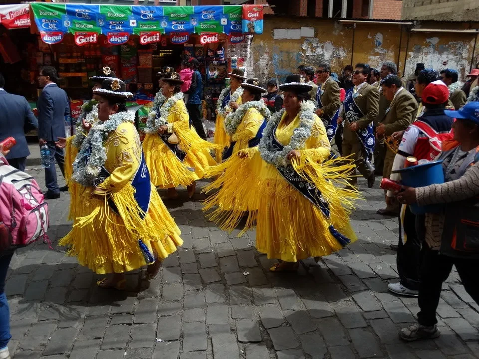 Una parata folcloristica colorata di costumi tradizionali si svolge in una strada storica.
