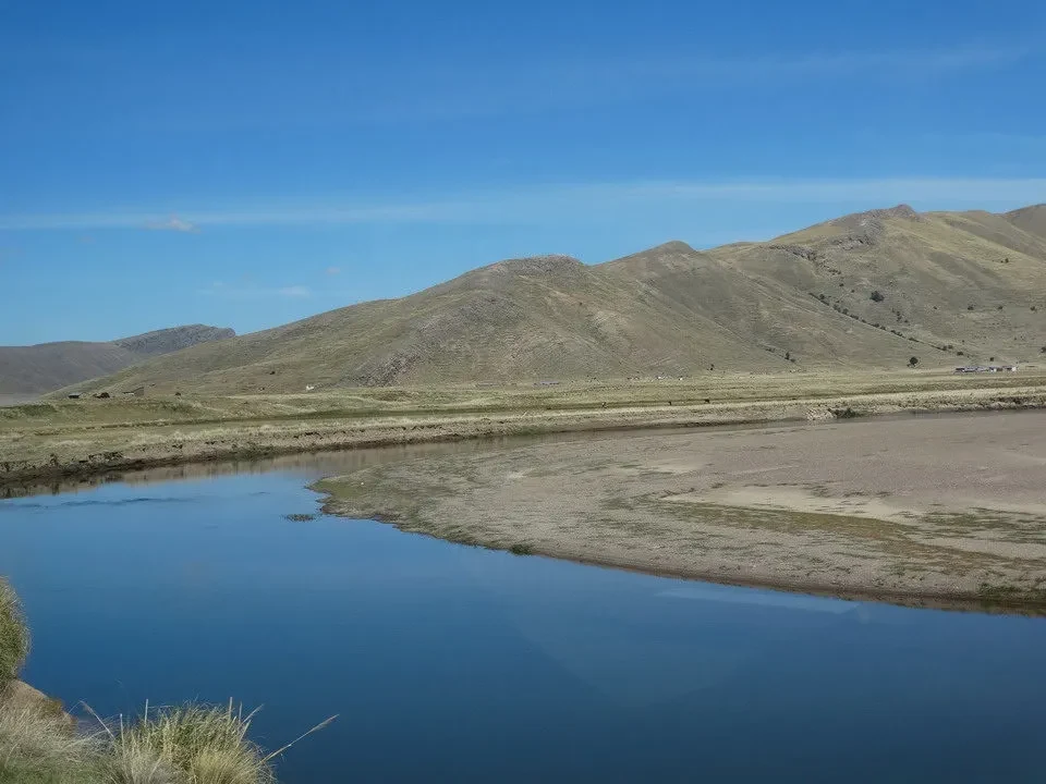 Paesaggio andino arido con un corpo d'acqua in primo piano.