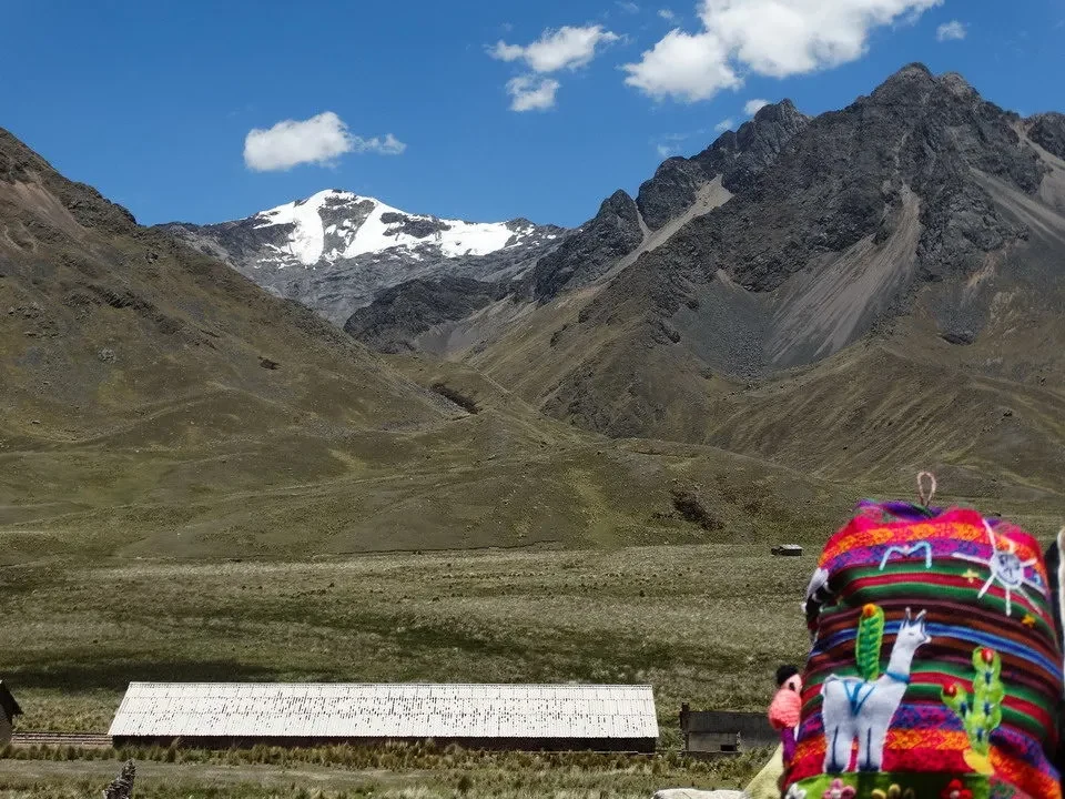 Montagne innevate si stagliano contro il cielo sopra un paesaggio andino.