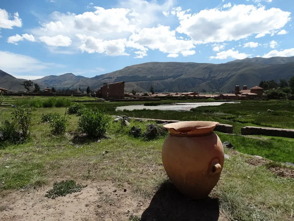 Rovine di un tempio andino con un vaso in primo piano nel paesaggio montano.