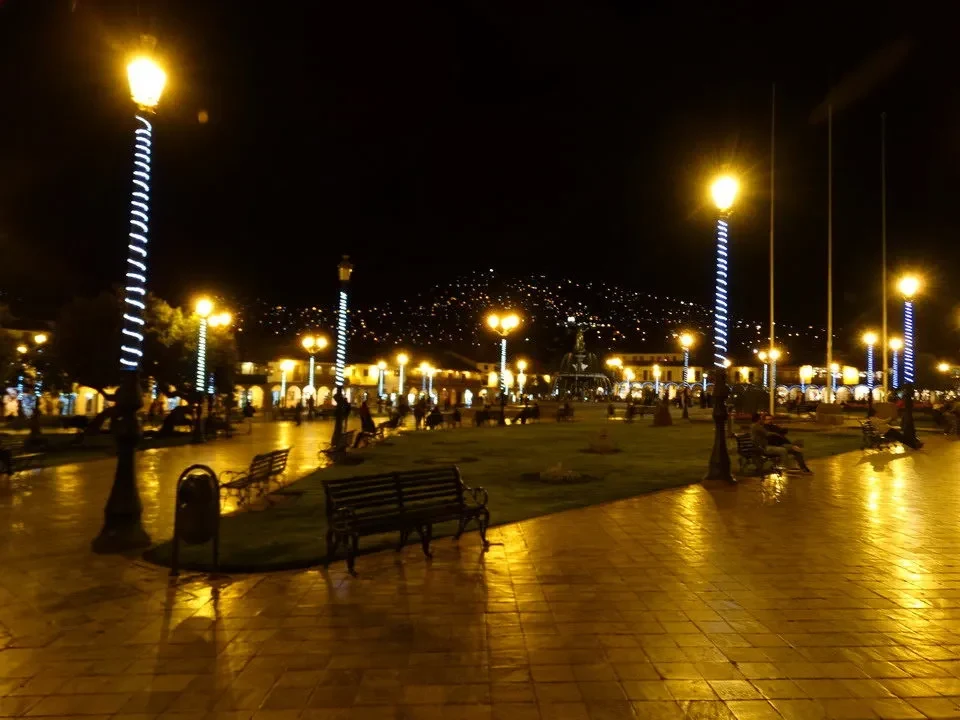 Veduta notturna di una piazza pubblica con lampioni luminosi e panchine.