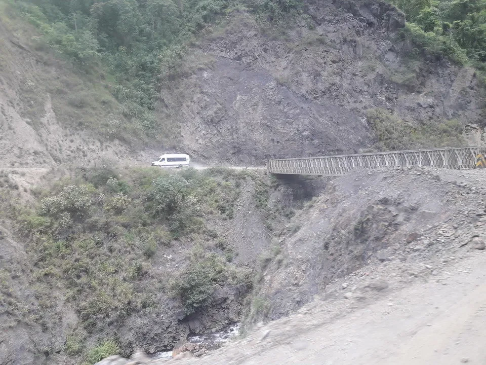 Una strada con un ponte attraversa un profondo canyon montano.