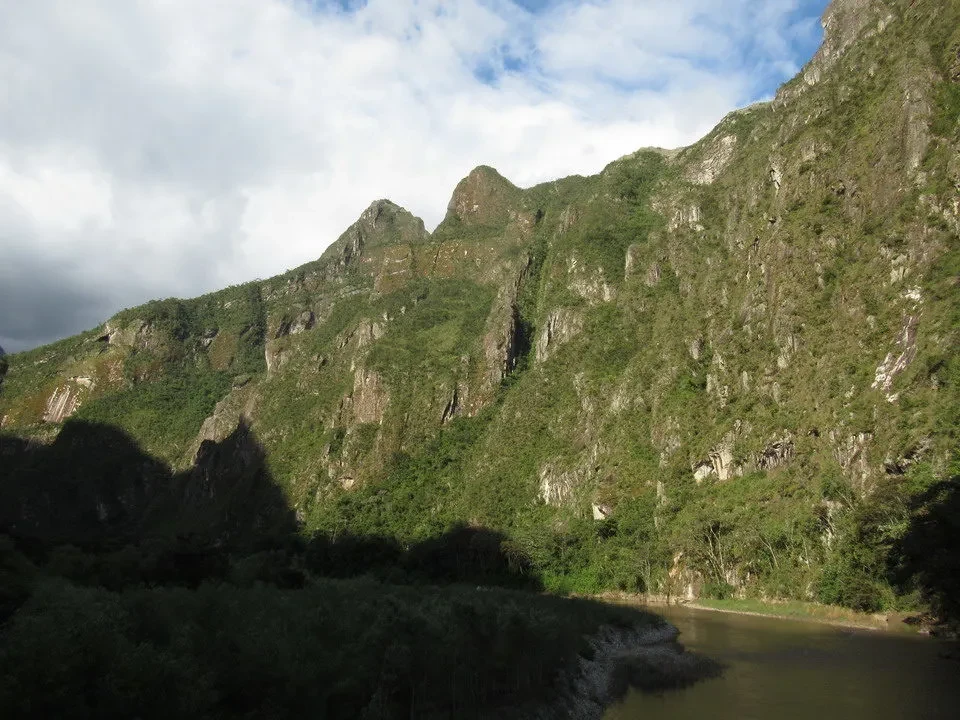 Paesaggio montano lussureggiante con un fiume che scorre alla base.