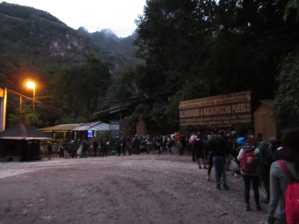 A group of people walks on a wooded path in a mountainous valley.