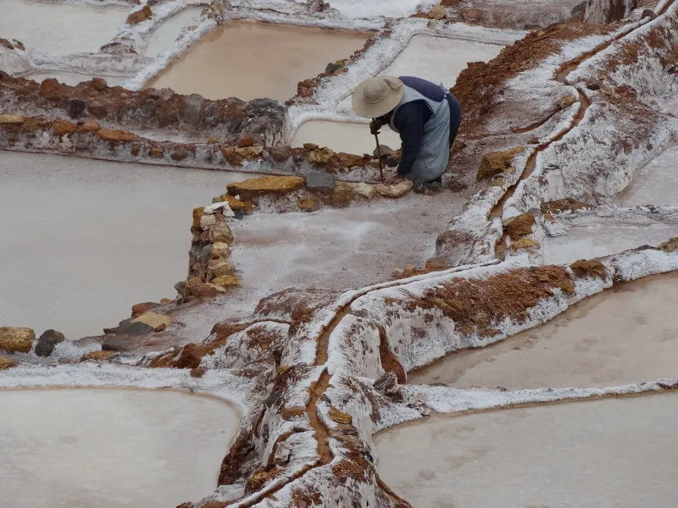 Una persona cammina attraverso i terrazzamenti salini di Maras.