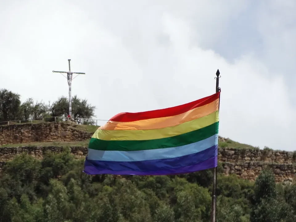 Una bandiera arcobaleno sventola sopra un paesaggio collinare in Perù o Bolivia.