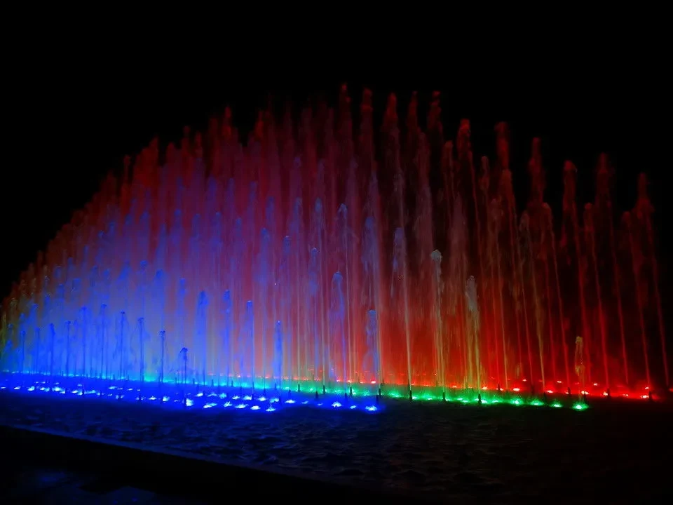 Fontane illuminate di rosso e blu creano uno spettacolo notturno sul lago.