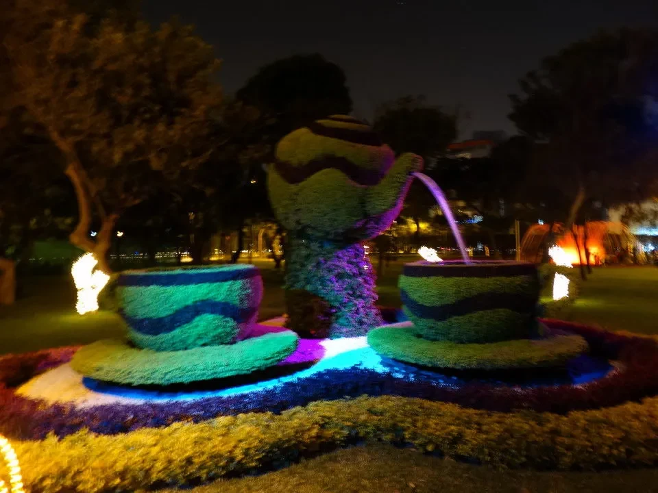 Fontana luminosa con giochi d'acqua in un giardino notturno.