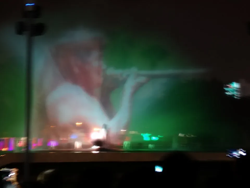 Una persona è illuminata in una scena notturna con effetti di luce verde.
