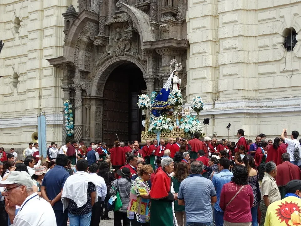 Processione religiosa davanti a un imponente edificio storico in stile coloniale.